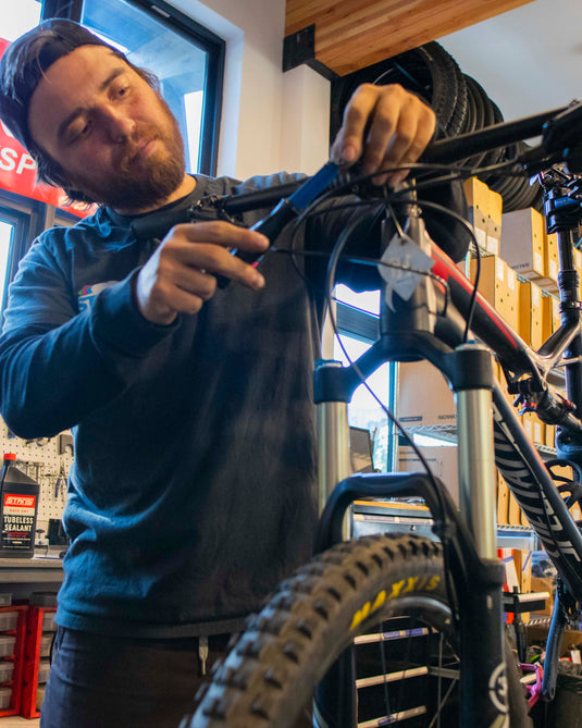 Person working on a bicycle in a workshop with tools and equipment around.